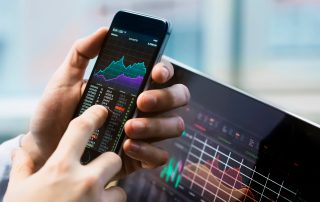 Young investor's hand holding a phone displaying a stock analysis chart with price trends.