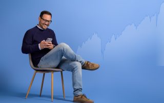 Happy man checking trending stocks on VectorVest via phone, smiling at hot market picks.